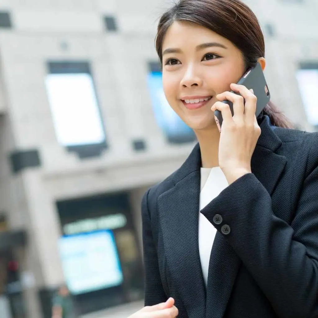 Smiling businesswoman talking on a smartphone while standing outdoors in a modern city environment