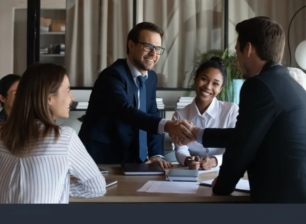 Business professionals shaking hands during a meeting, representing flexible pricing and partnership for Bridgeport businesses.