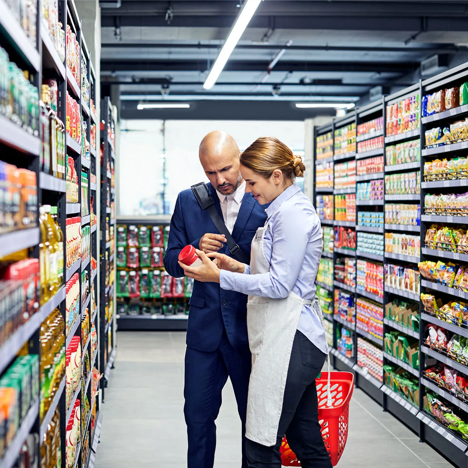 Retail manager discussing product details with staff in a supermarket aisle representing key business industries.