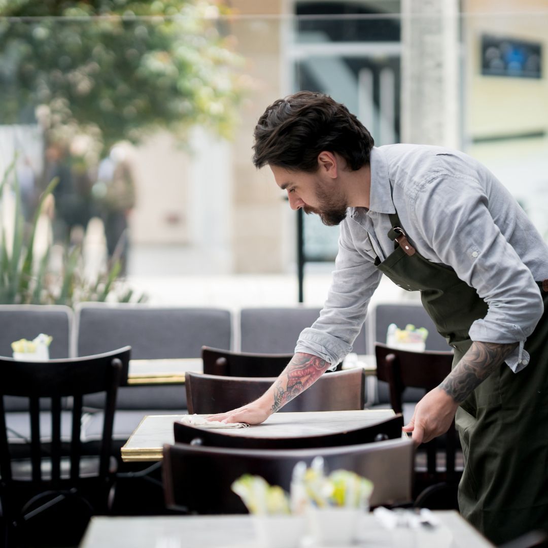 Restaurant worker cleaning tables in Bridgeport café, representing local industries and small business services in the community.