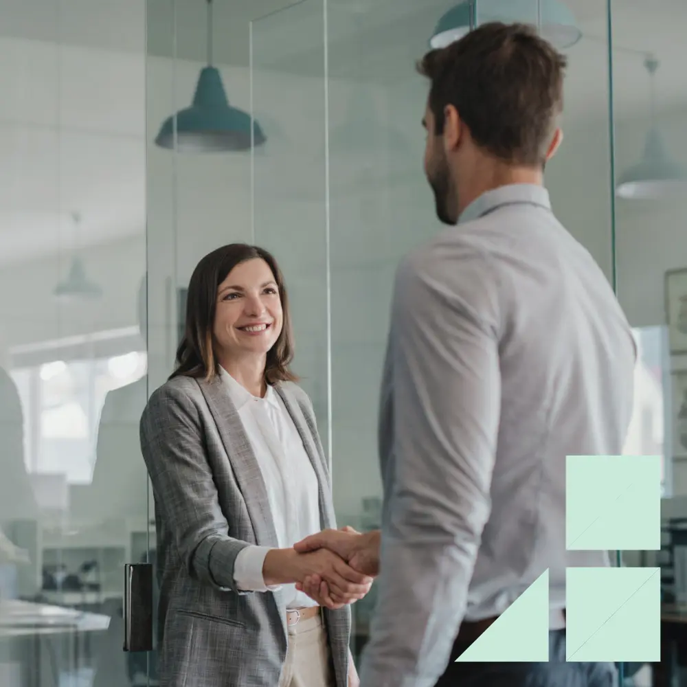 Two business professionals shaking hands in a modern office, symbolizing trust and partnership in simplified business planning