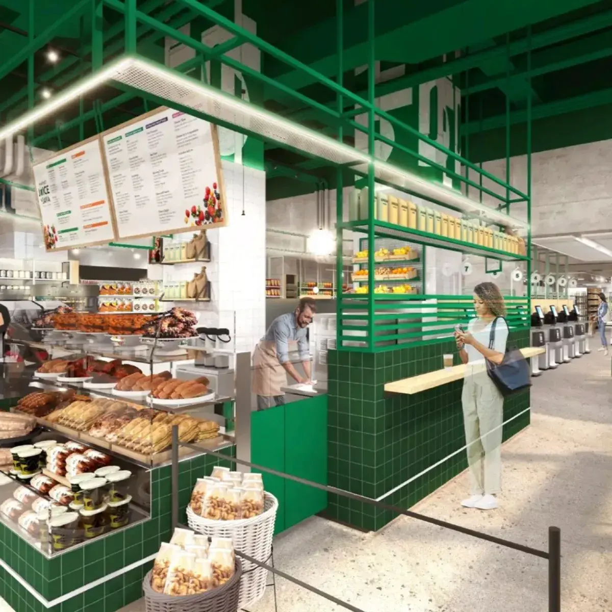 Modern café with green interior, displaying fresh bakery items and a worker serving a customer at the counter.