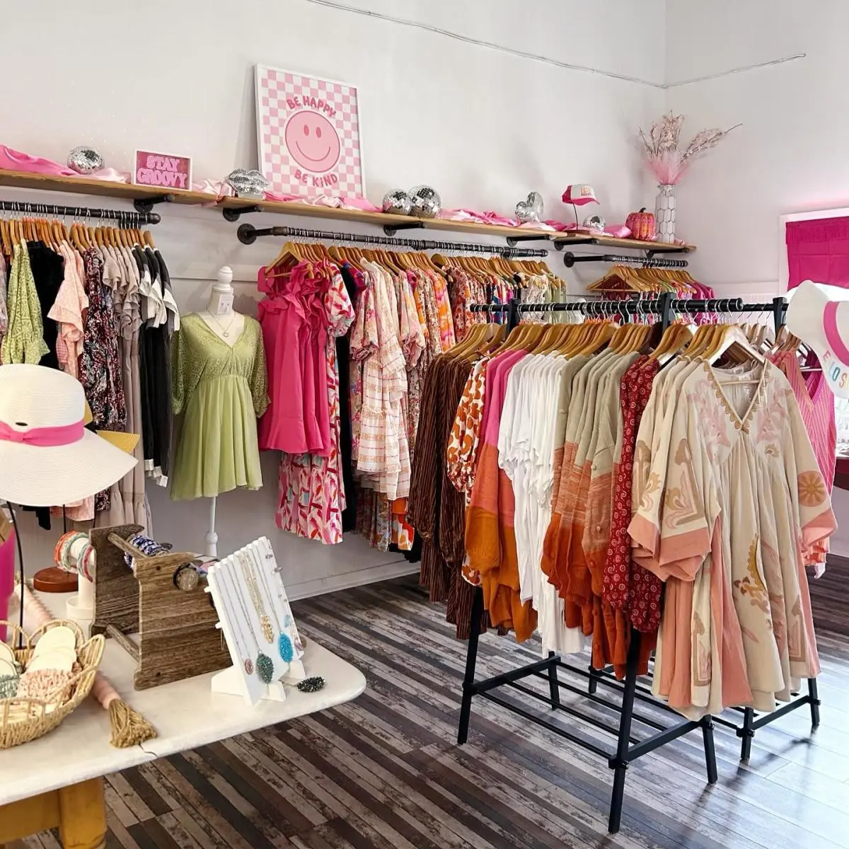Trendy boutique with colorful dresses, hats, and jewelry displays, featuring bright décor and a welcoming shopping space.